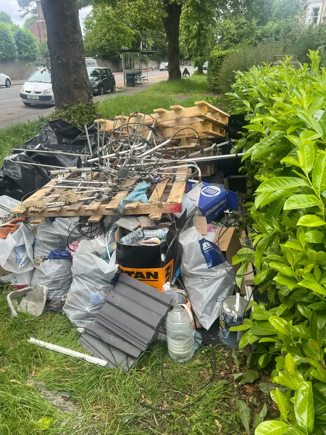 Pallets, rubble sacks and offcuts piled on a front lawn for builder’s waste clearance