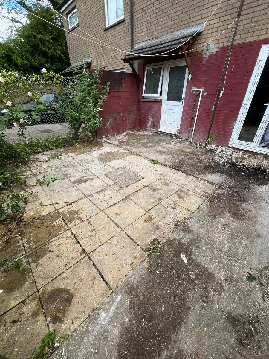 Cleared paved area beside a house after demolition waste was removed