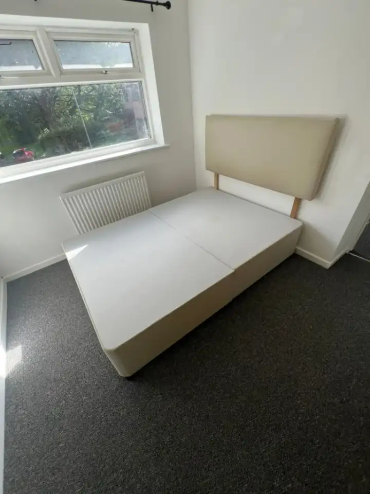 Divan bed base and headboard left in an emptied bedroom during a house clearance