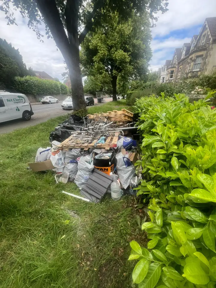 Rubble sacks and renovation waste piled beside a hedge awaiting collection