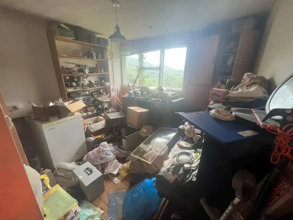 Cluttered room full of furniture and belongings before a house clearance