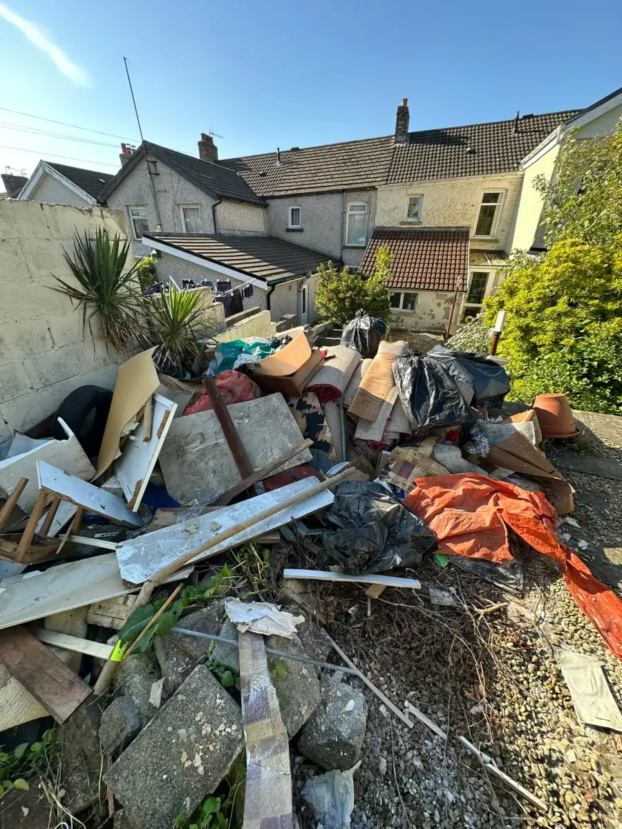 Large pile of rubble, timber and household waste in a back garden ready for removal